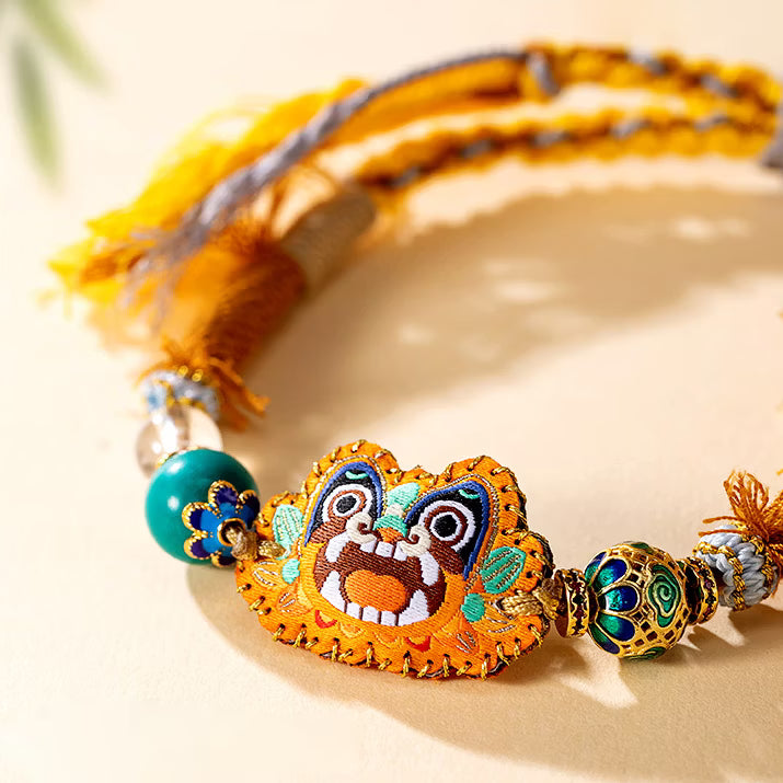 Close up of vibrant embroidered cat charm and hand-knotted cotton polyester cord on ethnic folk art bracelet