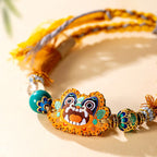Close up of vibrant embroidered cat charm and hand-knotted cotton polyester cord on ethnic folk art bracelet