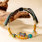 Close up of vibrant embroidered cat charm and hand-knotted cotton polyester cord on ethnic folk art bracelet