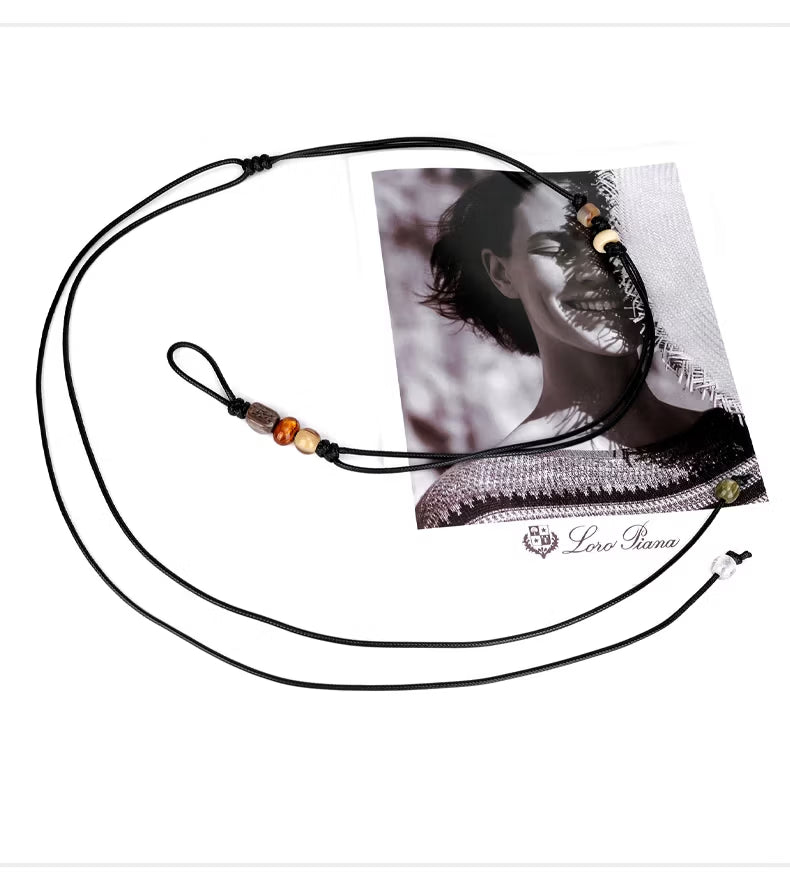 Close up of hand knotted black wax cord featuring colorful resin beads and thin adjustable tie