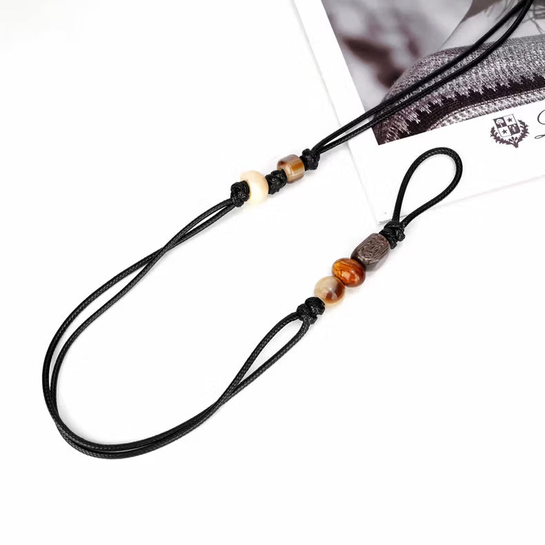 Close up of hand knotted black wax cord featuring colorful resin beads and thin adjustable tie
