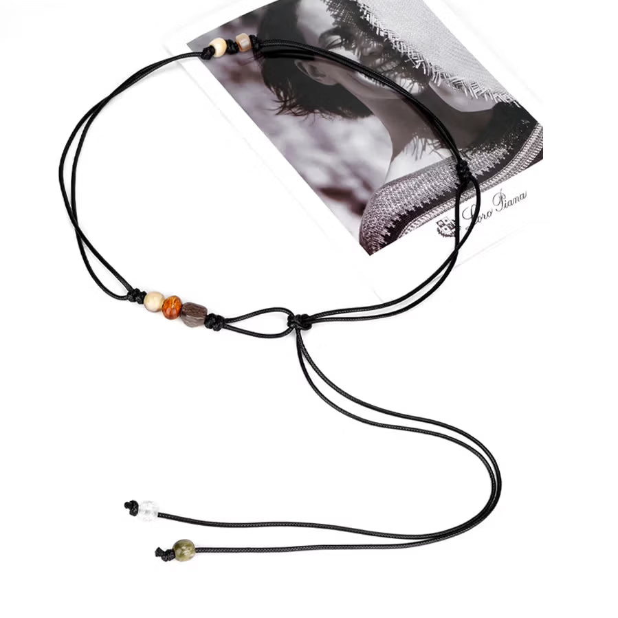 Close up of hand knotted black wax cord featuring colorful resin beads and thin adjustable tie