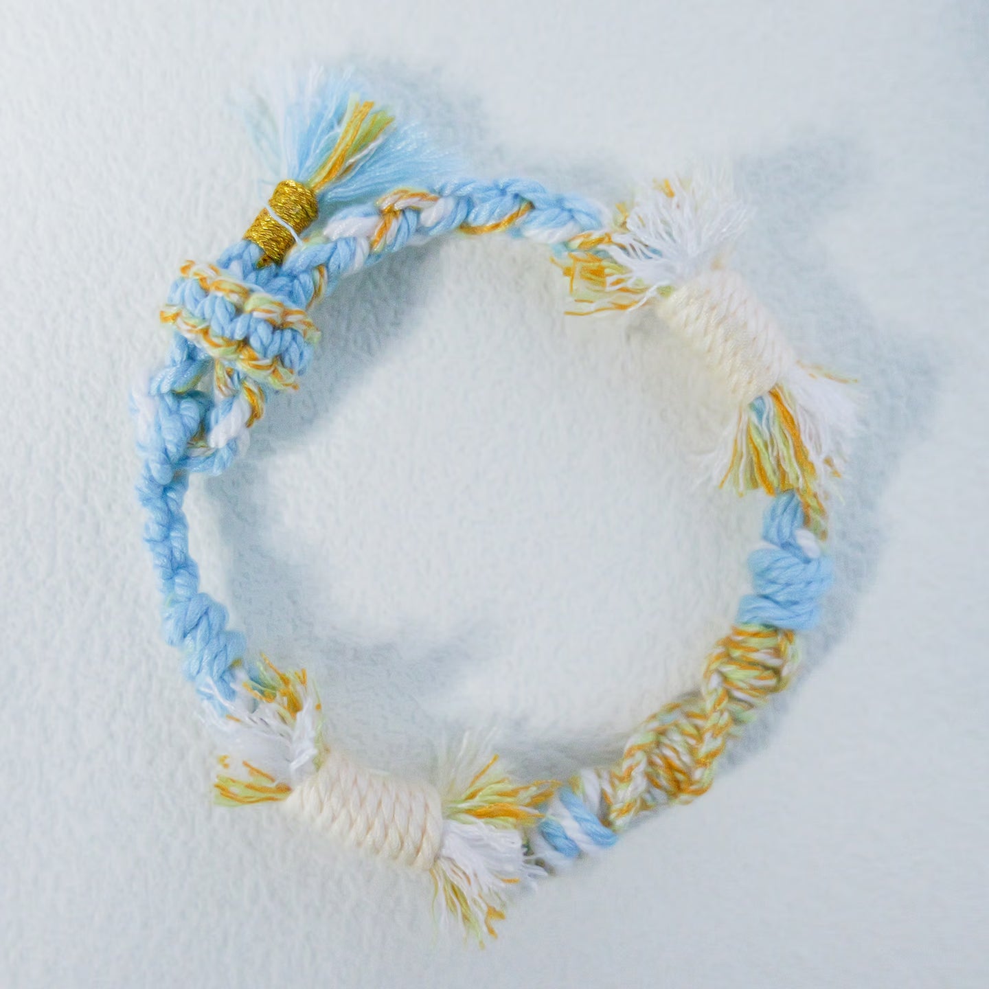 Handmade sky blue, cream and yellow Tibetan braided cord bracelet with fringe detail