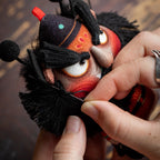 Close up of hand embroidered Zhong Kui face and reward good punish evil tag on herbal sachet charm