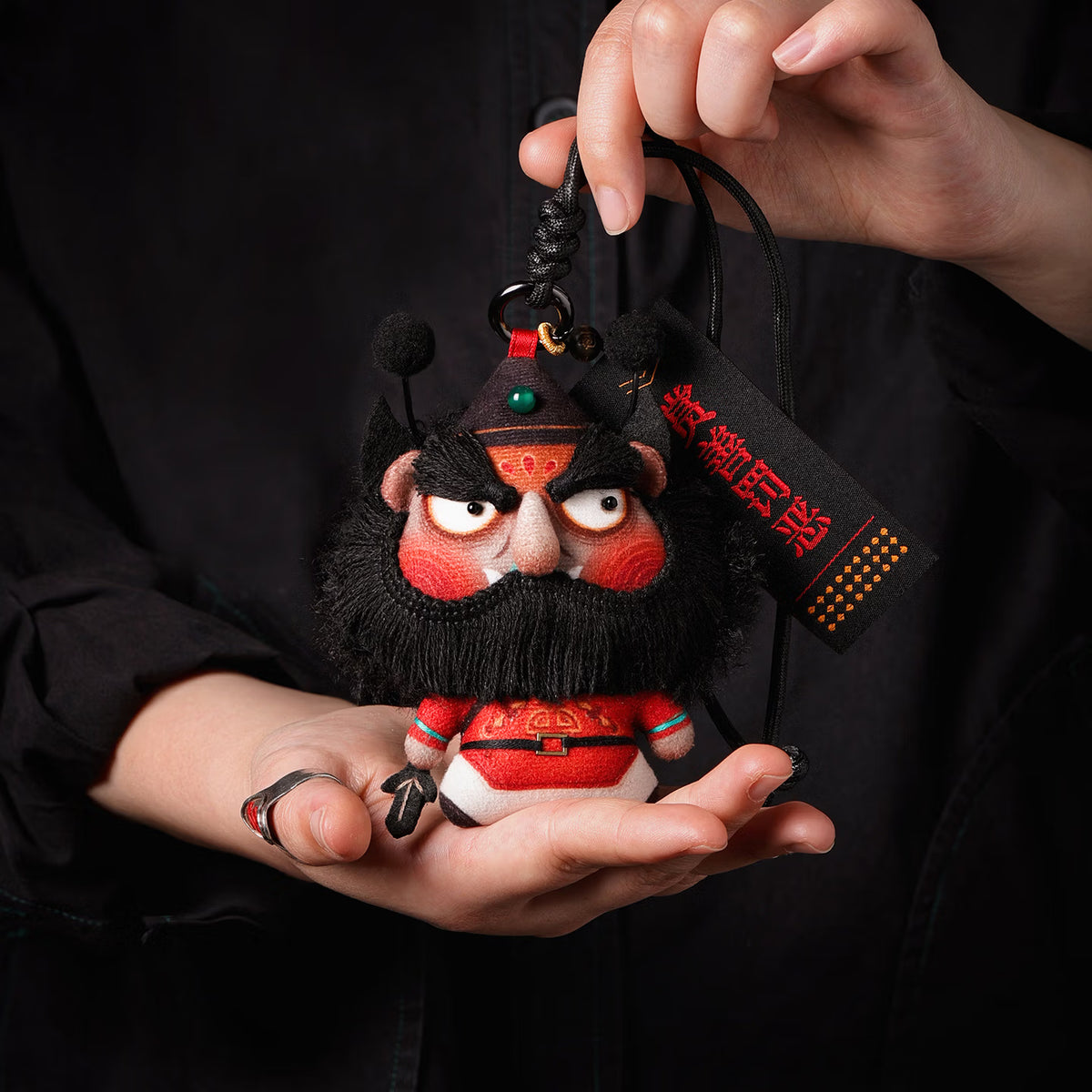 Handcrafted Zhong Kui demon slayer plush herbal sachet pendant with black beard and braided lanyard held in hands