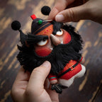 Close up of hand embroidered Zhong Kui face and reward good punish evil tag on herbal sachet charm