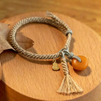 Handmade Tibetan braided cord bracelet with glowing amber stone pendant