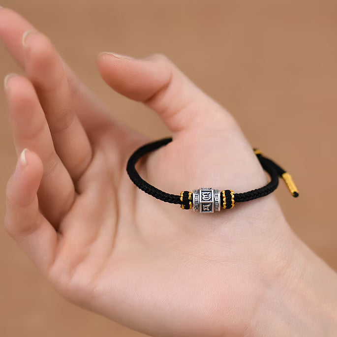 S999 fine silver Six-Syllable Mantra rotating bead on black hand-woven cord with gold accents