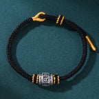 S999 fine silver Six-Syllable Mantra rotating bead on black hand-woven cord with gold accents
