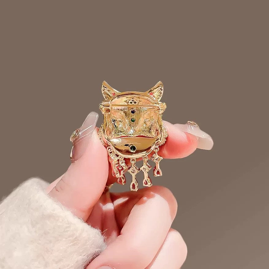 Close up of red enamel and faux rhinestone details on oriental lion dance suit lapel pin