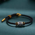 S999 fine silver Six-Syllable Mantra rotating bead on black hand-woven cord with gold accents
