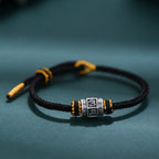 S999 fine silver Six-Syllable Mantra rotating bead on black hand-woven cord with gold accents