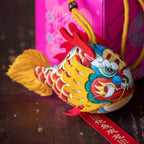 Smiling girl holding a handmade cute silk dragon carp sachet pendant with red blessing tag