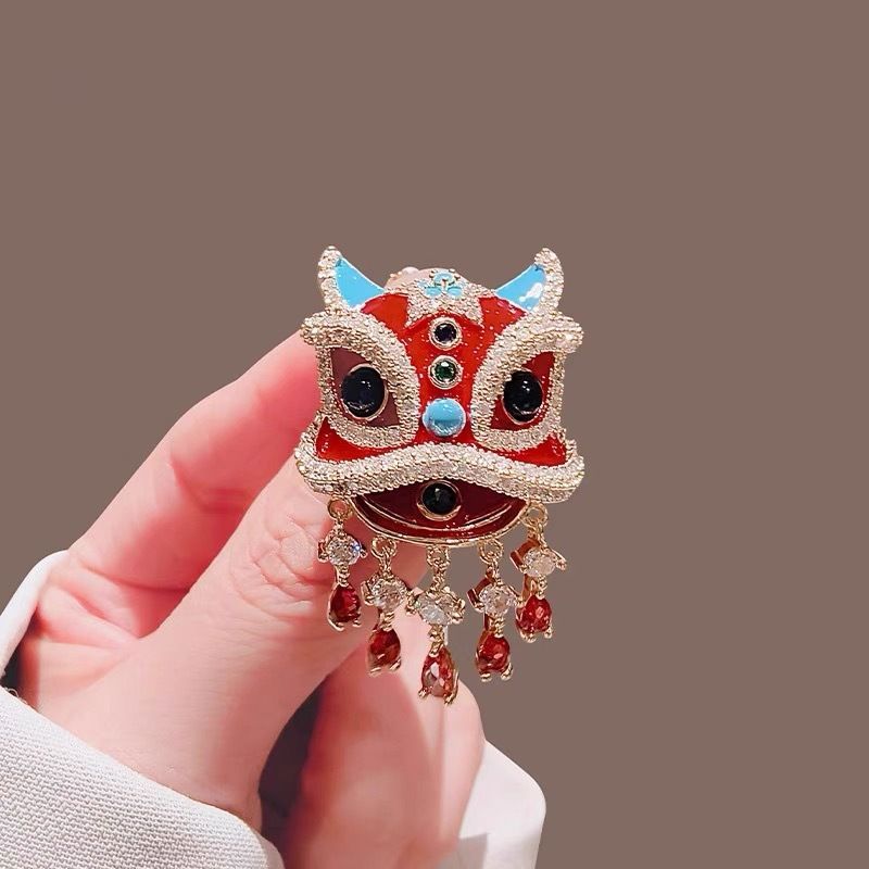 Close up of red enamel and faux rhinestone details on oriental lion dance suit lapel pin