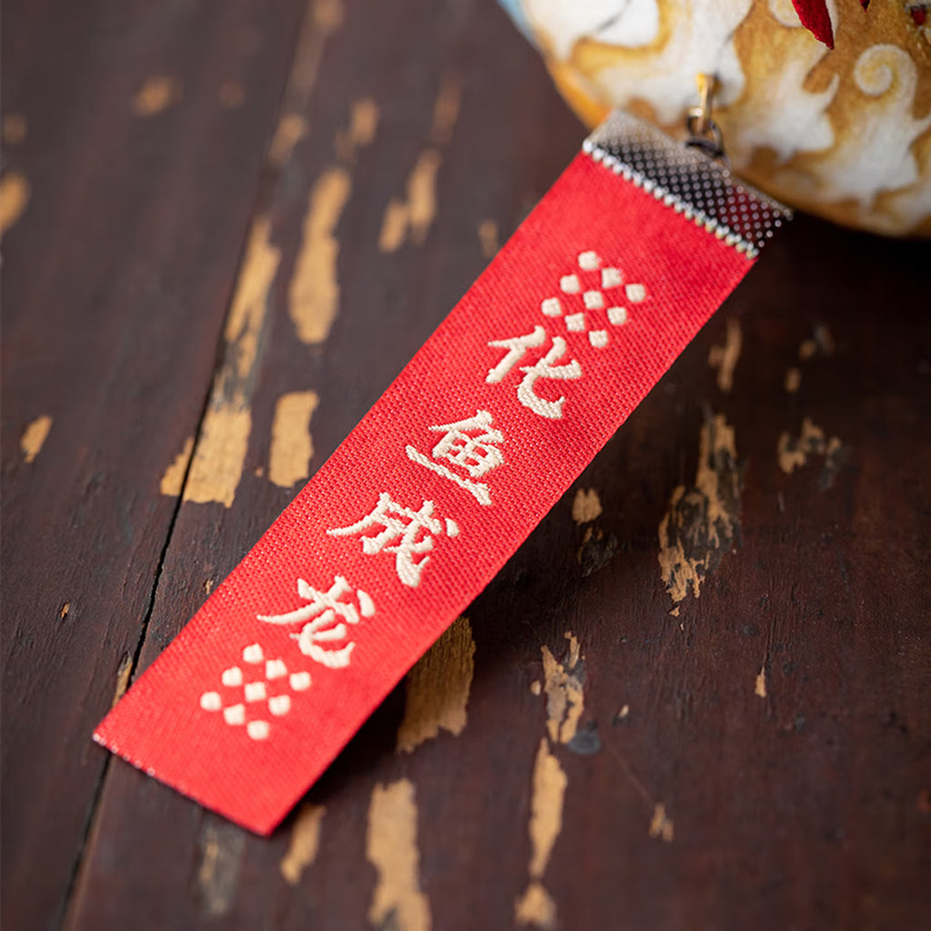 Smiling girl holding a handmade cute silk dragon carp sachet pendant with red blessing tag