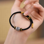 S999 fine silver Six-Syllable Mantra rotating bead on black hand-woven cord with gold accents