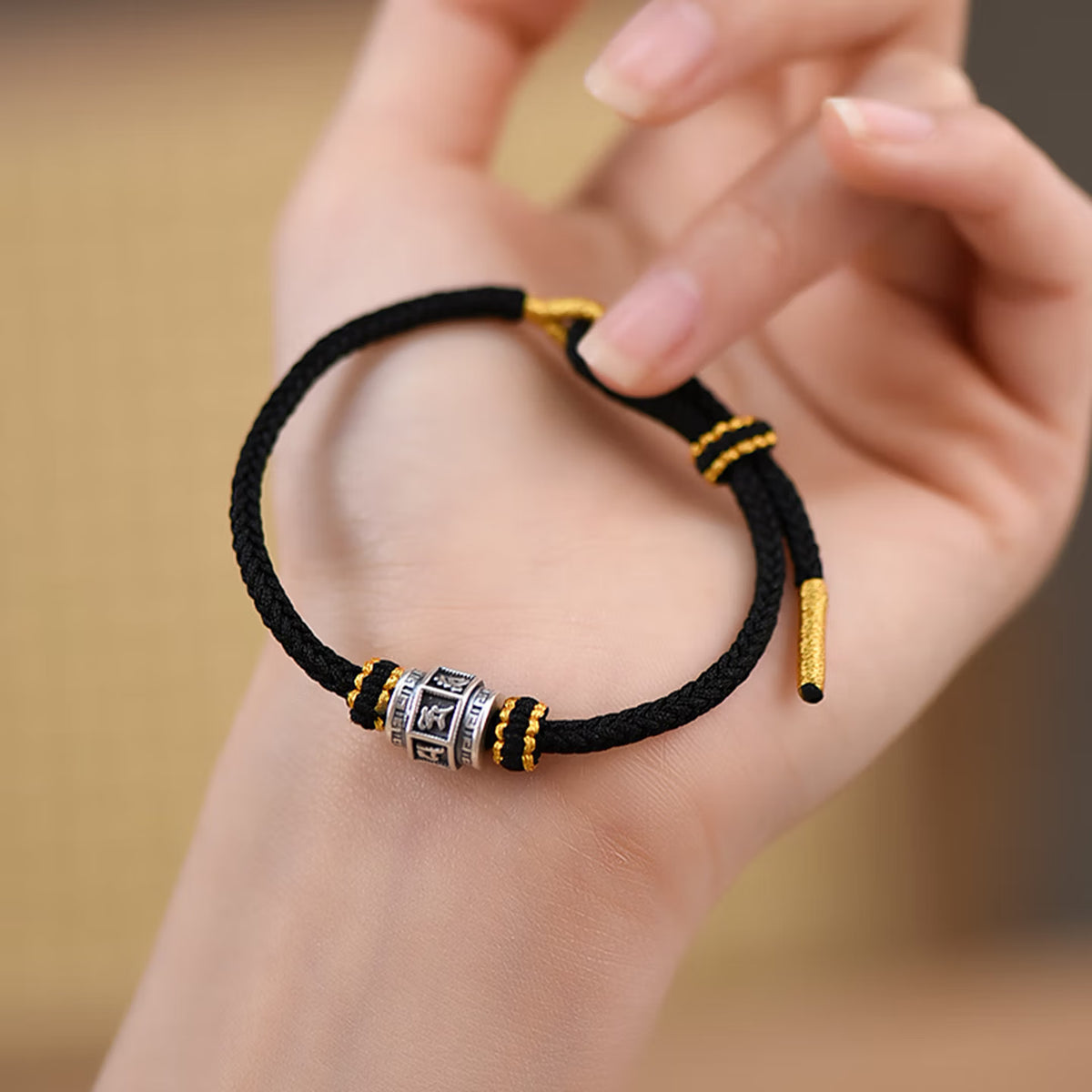 S999 fine silver Six-Syllable Mantra rotating bead on black hand-woven cord with gold accents
