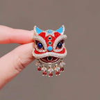 Close up of red enamel and faux rhinestone details on oriental lion dance suit lapel pin