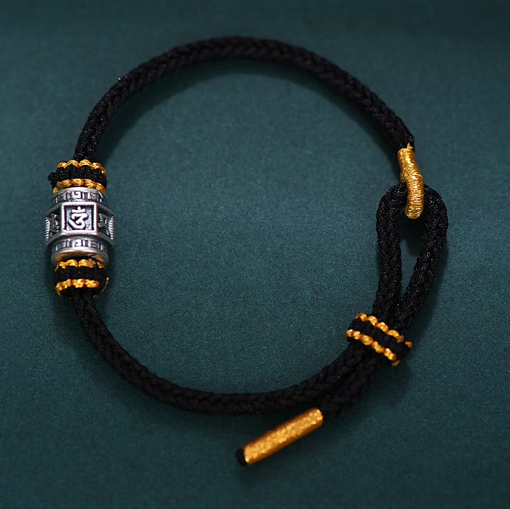 S999 fine silver Six-Syllable Mantra rotating bead on black hand-woven cord with gold accents