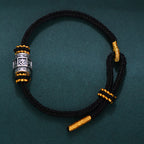 S999 fine silver Six-Syllable Mantra rotating bead on black hand-woven cord with gold accents