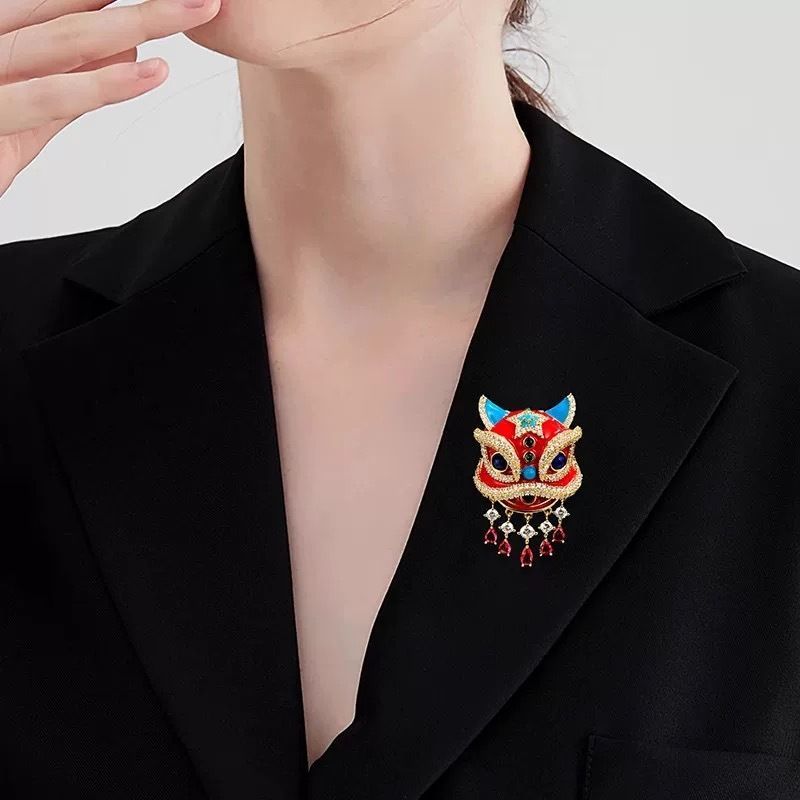 Close up of red enamel and faux rhinestone details on oriental lion dance suit lapel pin