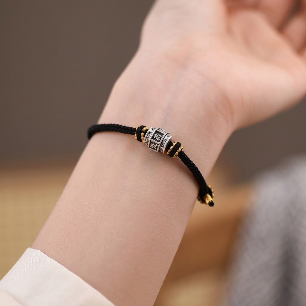 S999 fine silver Six-Syllable Mantra rotating bead on black hand-woven cord with gold accents