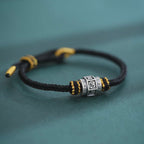 S999 fine silver Six-Syllable Mantra rotating bead on black hand-woven cord with gold accents