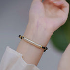 English: S999 fine silver Heart Sutra curved tube bracelet with gold gilded calligraphy on dark braided cord