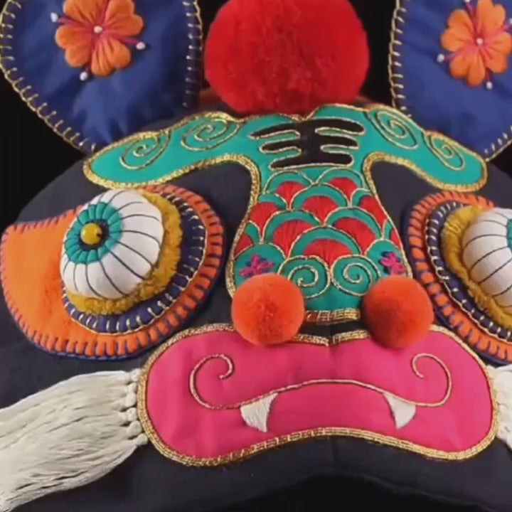 Close up of vibrant hand-embroidered tiger face features and cotton ear flaps on traditional folk hat