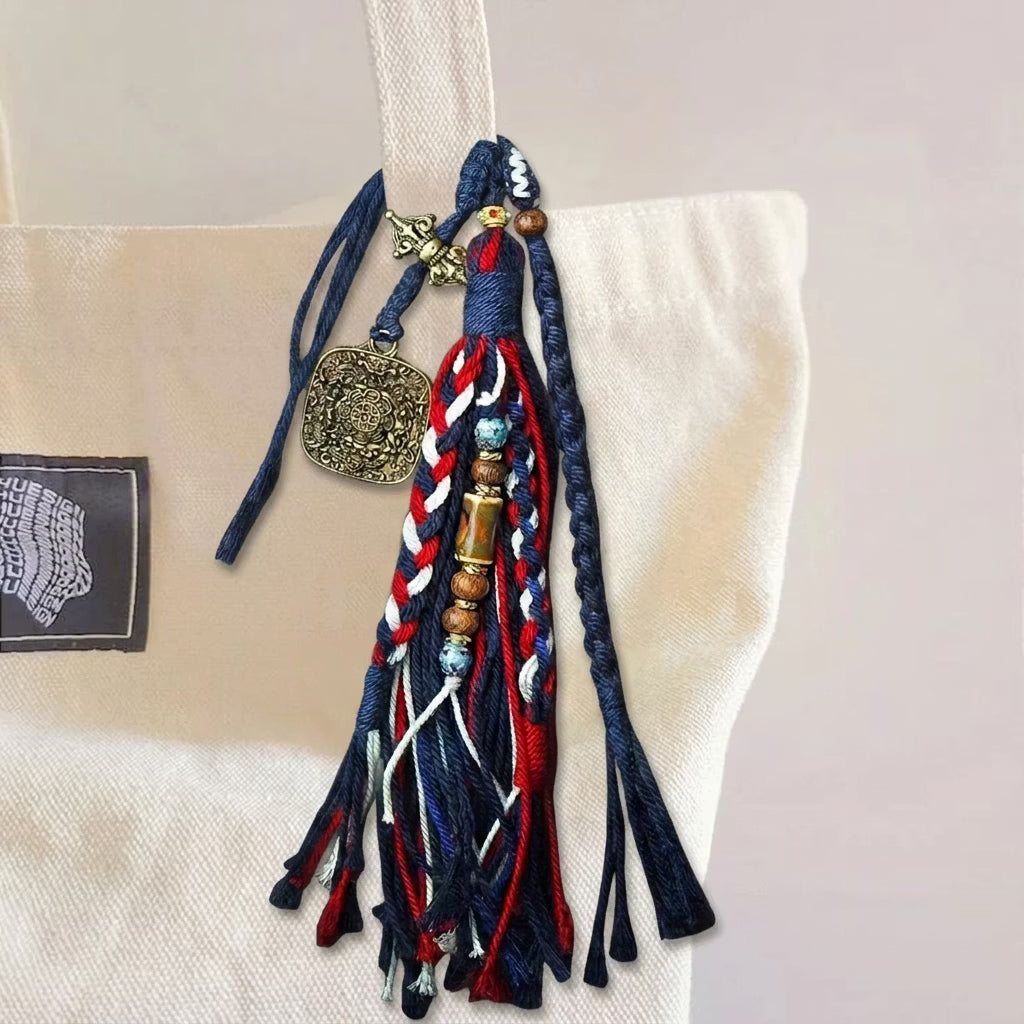 Close up of hand knotted multi-colored cotton rope strands featuring carved metal medallion and wooden beads