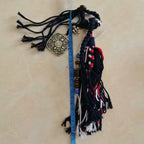 Close up of hand knotted multi-colored cotton rope strands featuring carved metal medallion and wooden beads